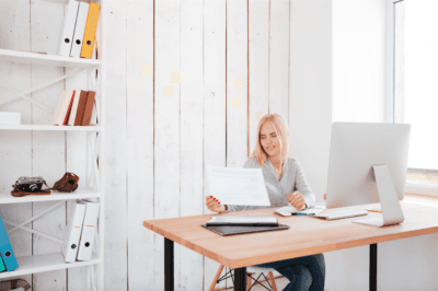 Emprendedora revisando documentos en un escritorio con ordenador