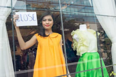 Mujer mostrando un cartel de cierre en el escaparate de una tienda