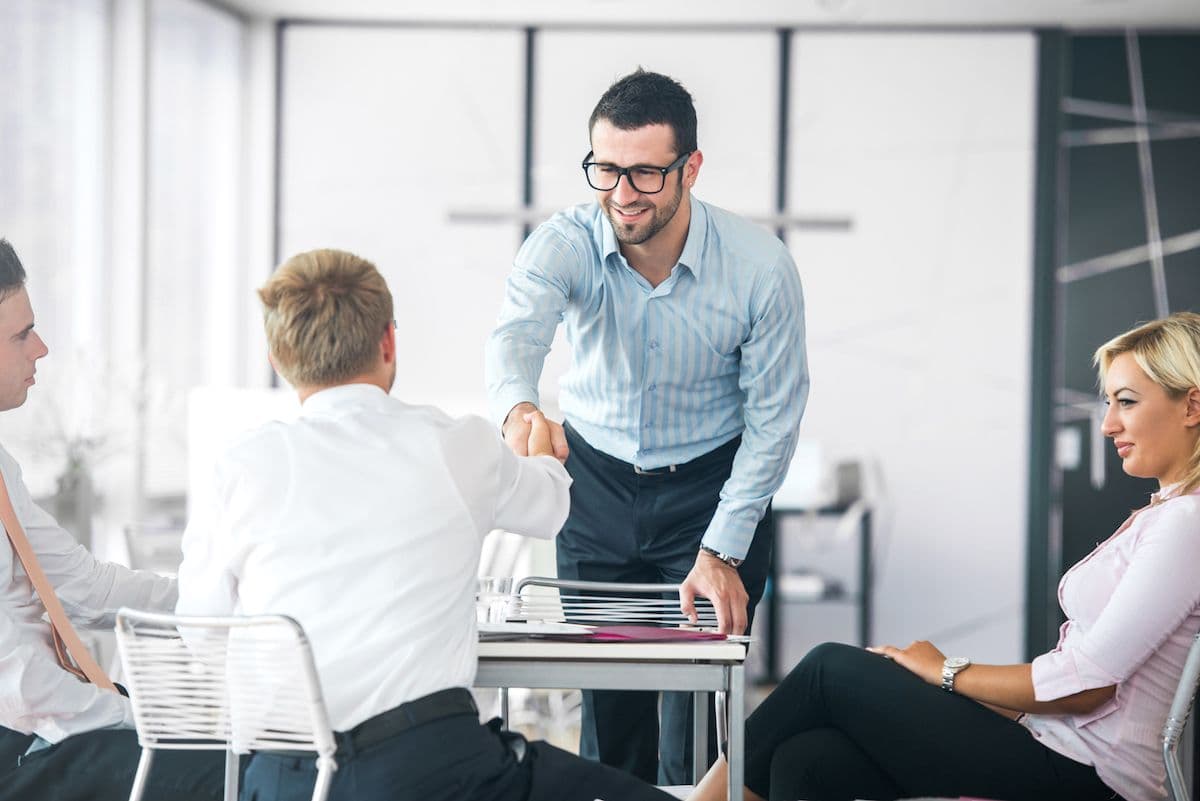 Personas estrechándose la mano durante una reunión de negocios