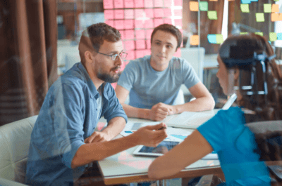 Tres personas conversando alrededor de una mesa de trabajo