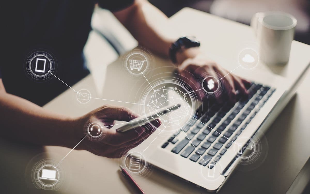 Persona usando un portátil y un móvil con iconos de servicios digitales